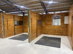 Interior of a custom pole barn with wooden horse stalls and metal framing built by Southern Pro Pole Barns & Buildings